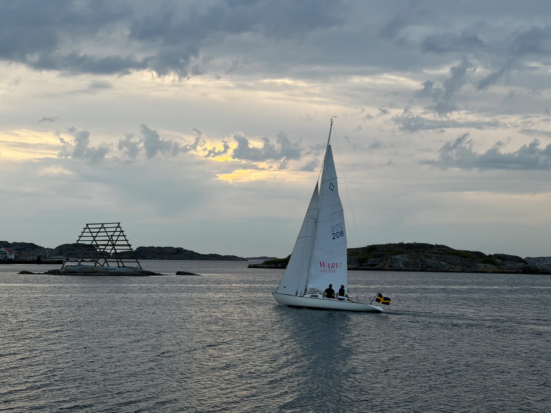 Segelbåt med Warv Gruppen på seglet i solnedgång på Västkusten